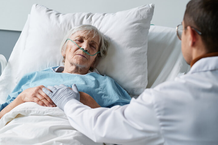 nurse with patient by hospital bed