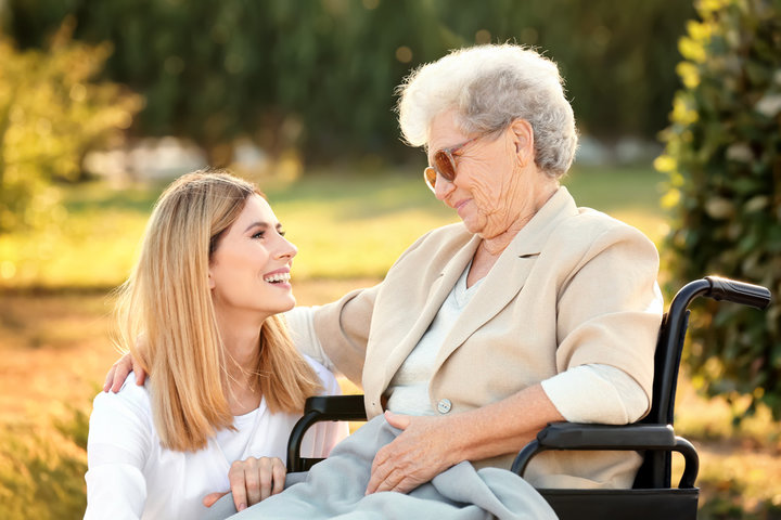 older woman with family visiting her outside in wheelchair at care home