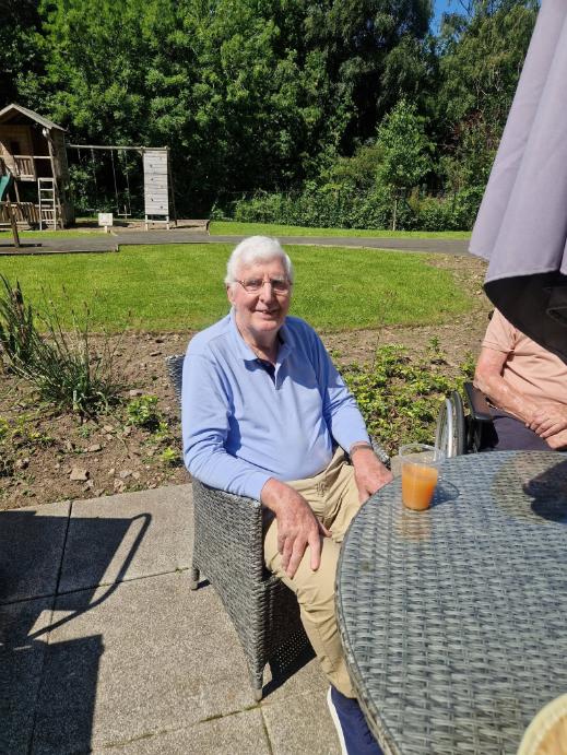 resident smiling with a drink in the garden