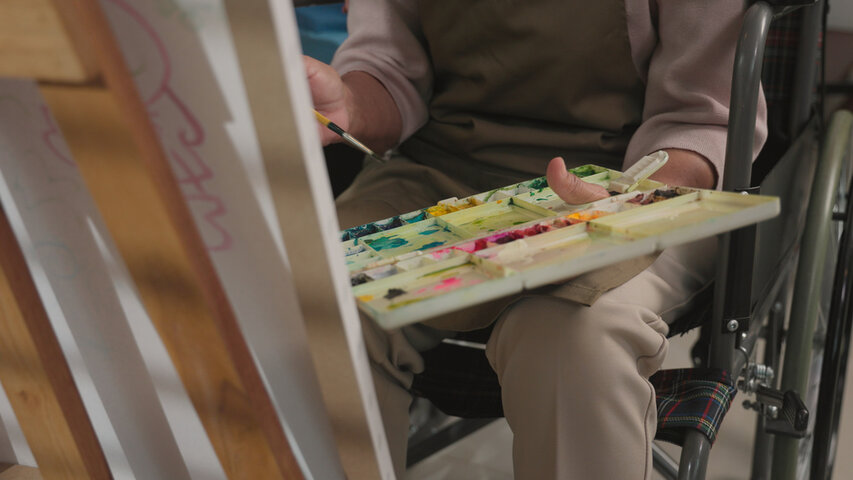 senior person painting in a wheelchair at a care home